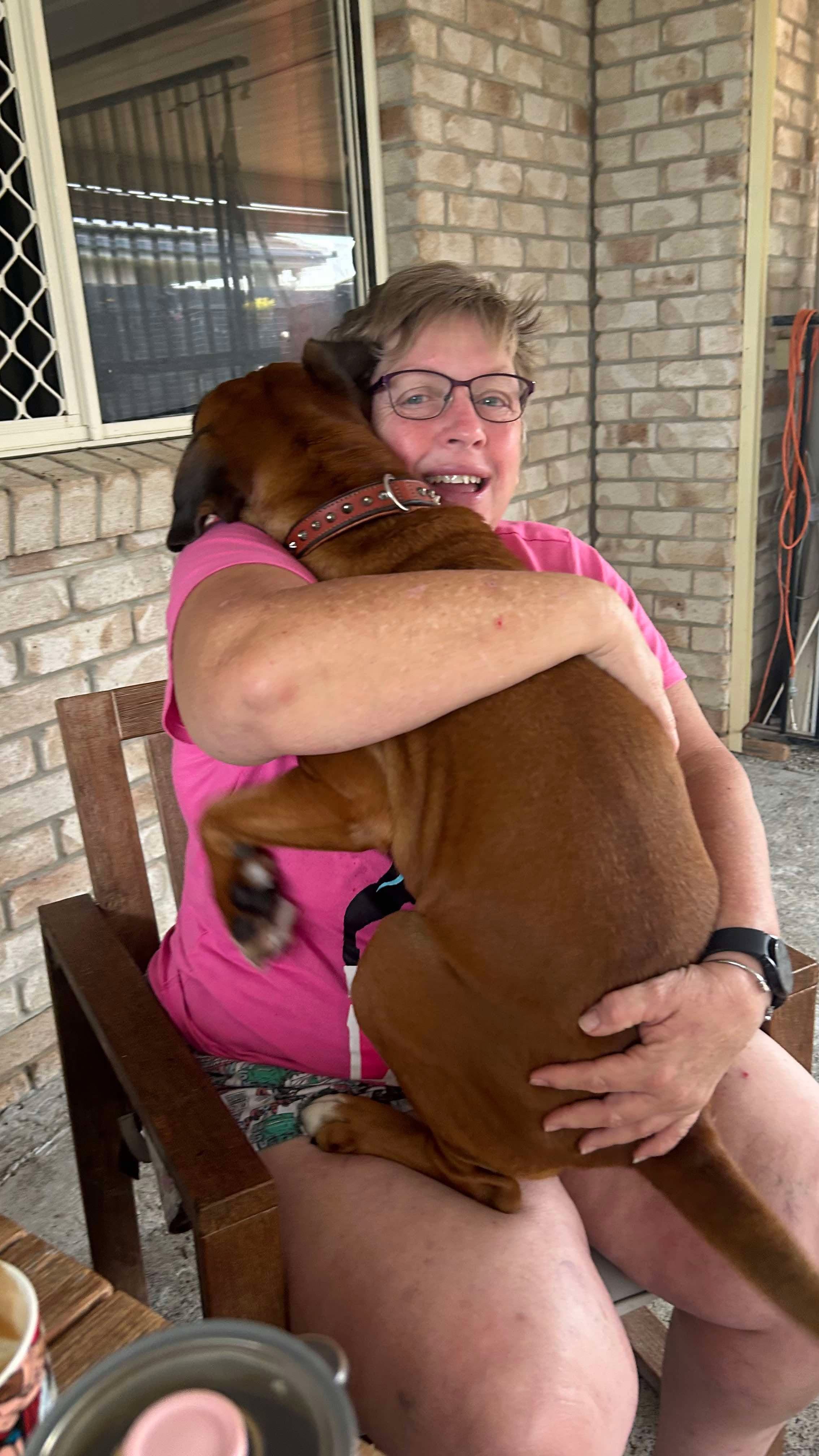 Kay smiling as she hugs Asgard in a chair